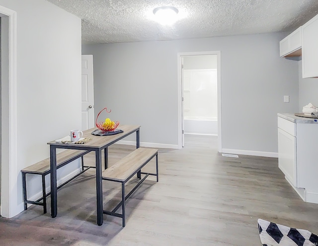 dining room with a textured ceiling and light hardwood / wood-style flooring