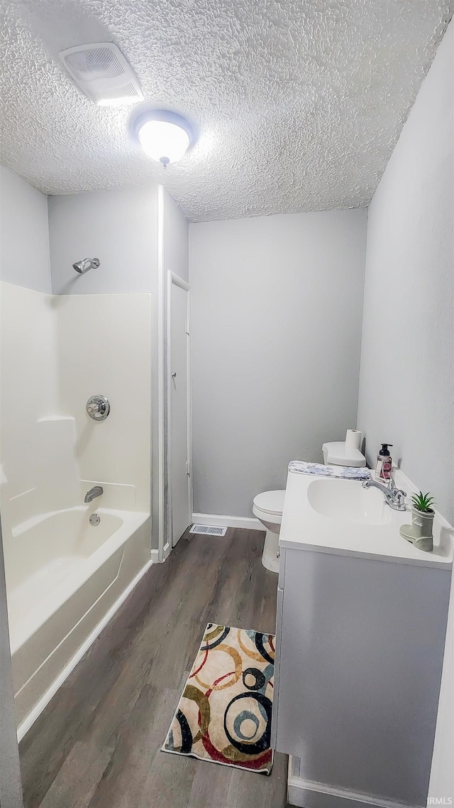 full bathroom with shower / washtub combination, wood-type flooring, vanity, toilet, and a textured ceiling