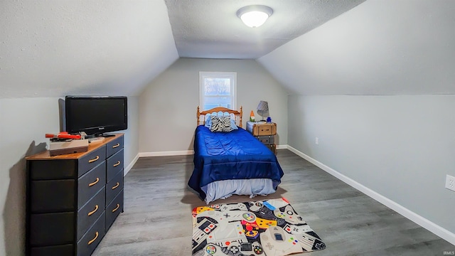 bedroom with hardwood / wood-style flooring, lofted ceiling, and a textured ceiling