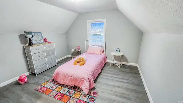 bedroom with vaulted ceiling, hardwood / wood-style floors, and a textured ceiling