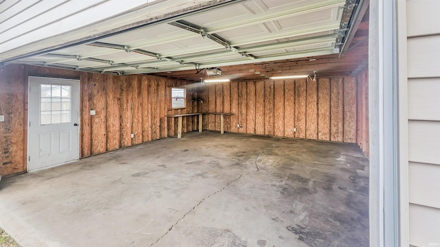 garage with a garage door opener and wooden walls