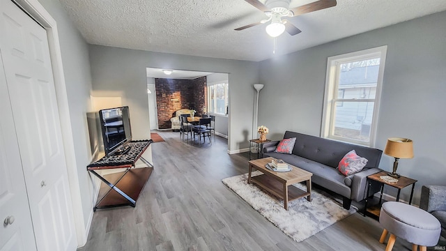 living room with ceiling fan, a textured ceiling, and light wood-type flooring