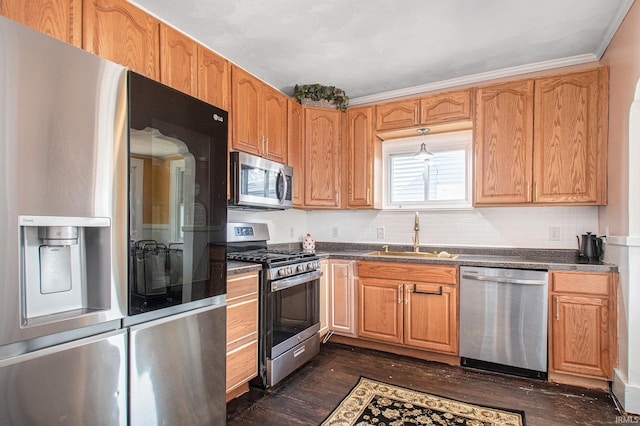 kitchen with dark wood-type flooring, appliances with stainless steel finishes, crown molding, and sink