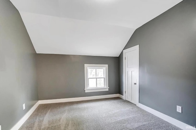 carpeted spare room with vaulted ceiling