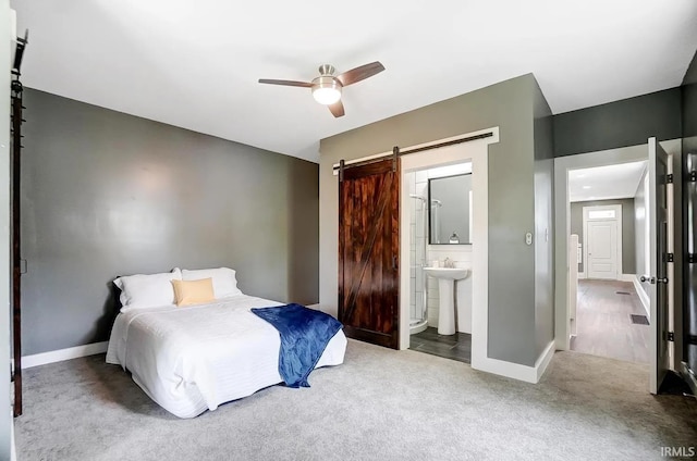 bedroom featuring ensuite bathroom, sink, ceiling fan, a barn door, and carpet