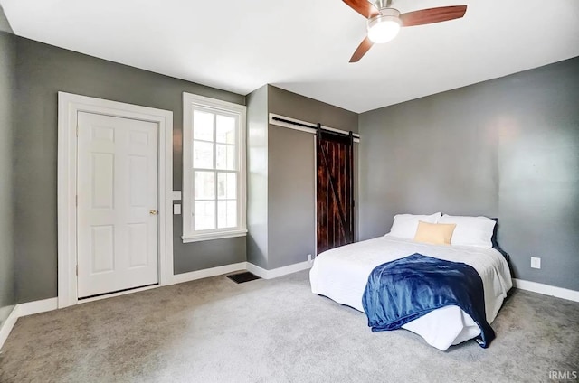 carpeted bedroom featuring a barn door and ceiling fan