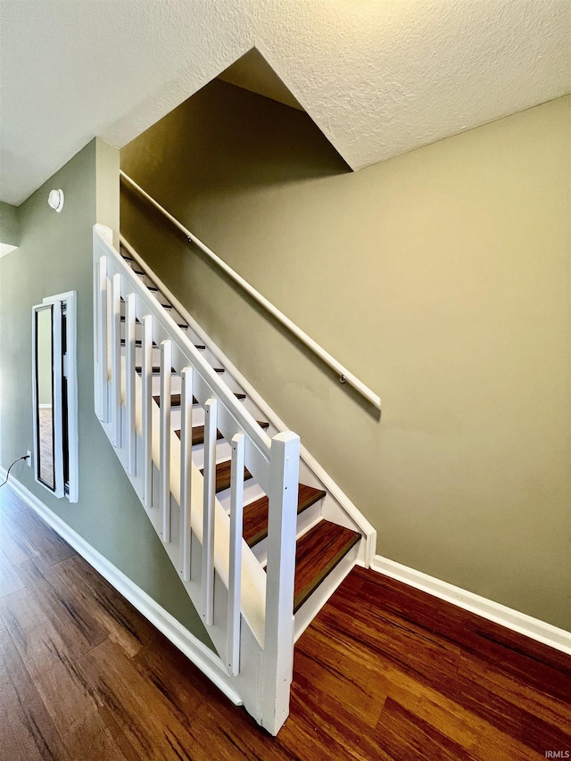 stairs featuring wood-type flooring and a textured ceiling