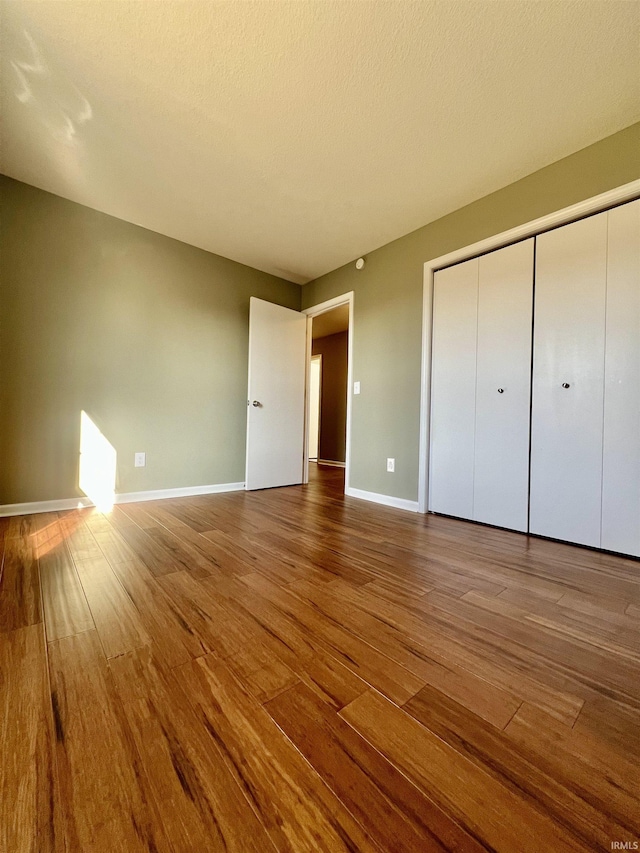 unfurnished bedroom featuring wood-type flooring, a closet, and a textured ceiling