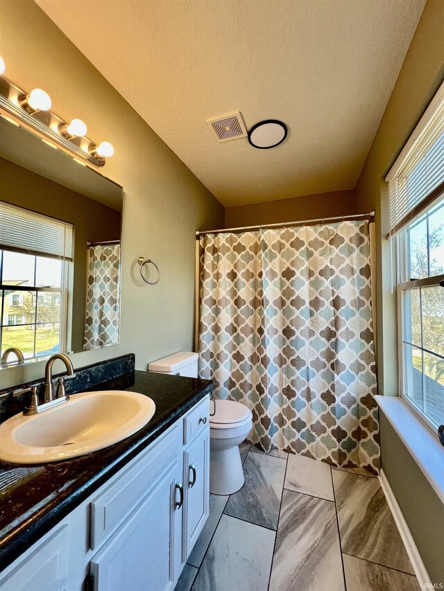 bathroom featuring vanity, toilet, and a textured ceiling