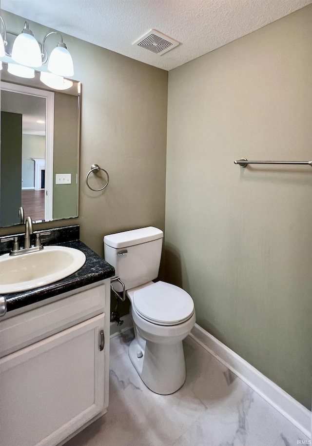 bathroom featuring vanity, a textured ceiling, and toilet