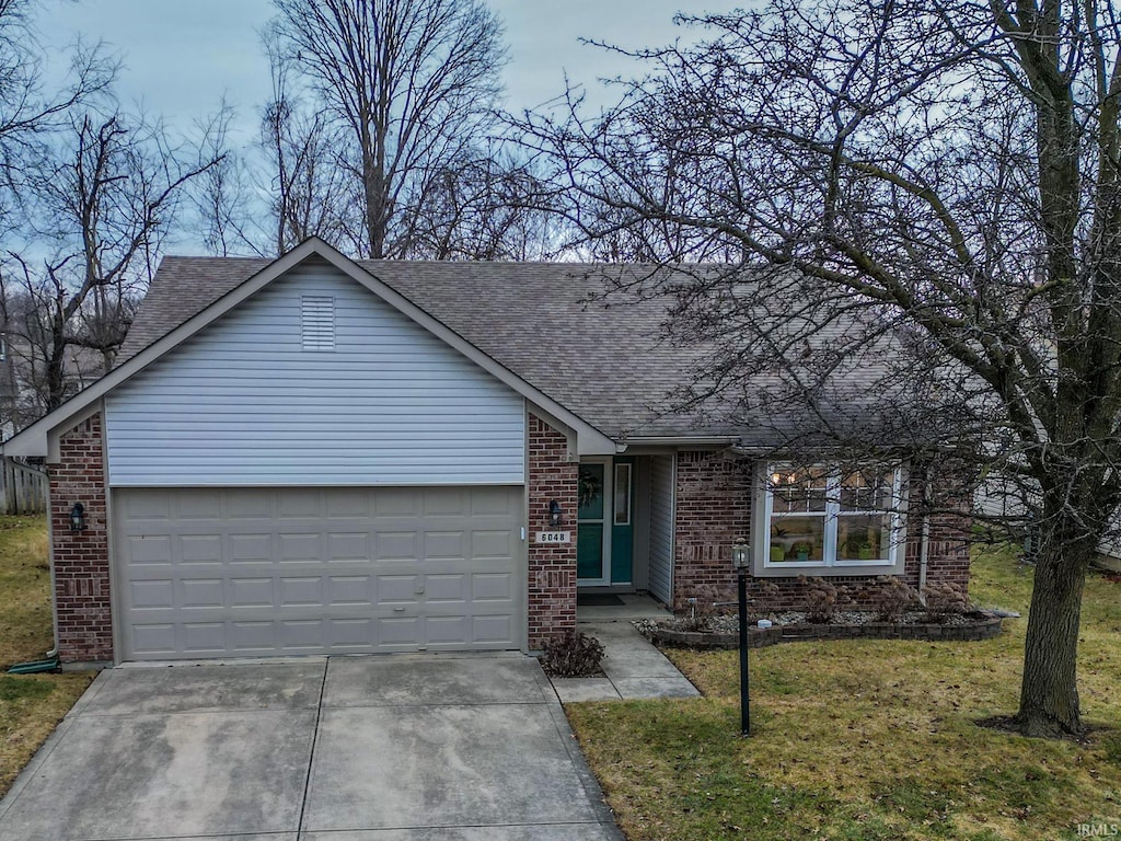 ranch-style home with a garage and a front lawn