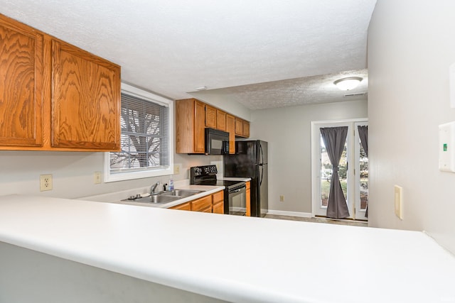 kitchen with sink, a wealth of natural light, a textured ceiling, and black appliances