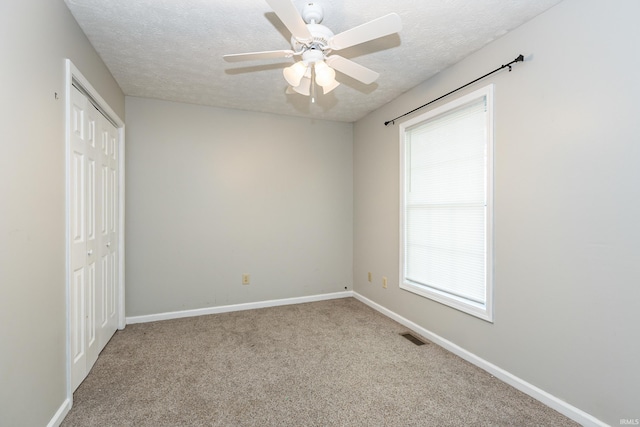 spare room featuring light carpet, ceiling fan, and a textured ceiling