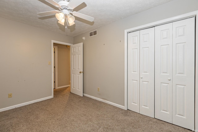 unfurnished bedroom featuring light carpet, ceiling fan, a closet, and a textured ceiling