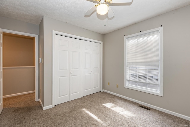 unfurnished bedroom with multiple windows, a textured ceiling, and carpet flooring