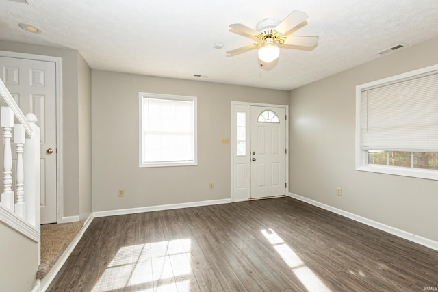 entryway with dark wood-type flooring, ceiling fan, and a textured ceiling