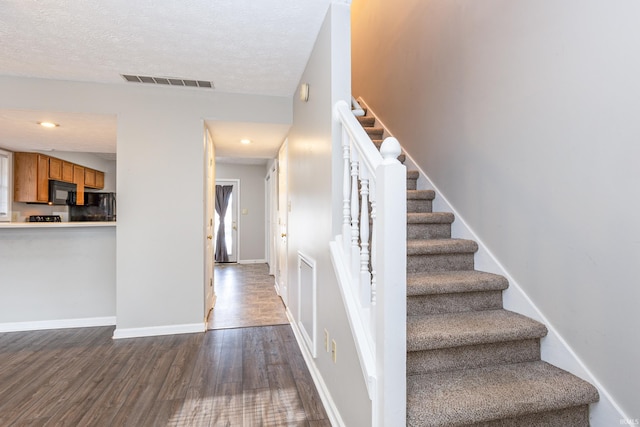 staircase with hardwood / wood-style flooring and a textured ceiling