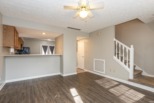 unfurnished living room featuring ceiling fan, dark hardwood / wood-style flooring, and a textured ceiling