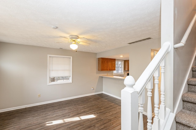 unfurnished living room with ceiling fan, dark wood-type flooring, and a textured ceiling