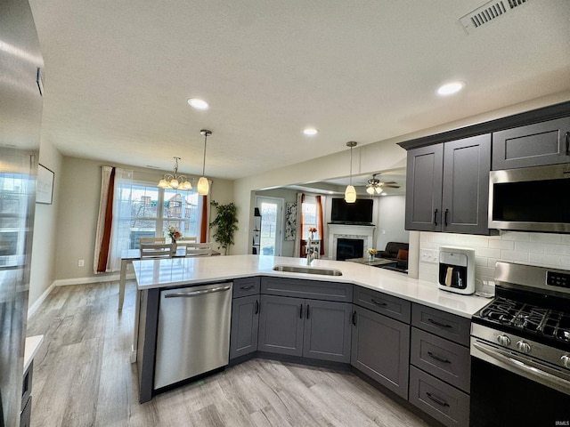 kitchen with sink, decorative backsplash, hanging light fixtures, kitchen peninsula, and stainless steel appliances