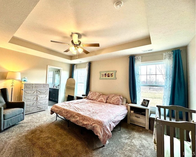 bedroom featuring carpet flooring, a tray ceiling, and a textured ceiling