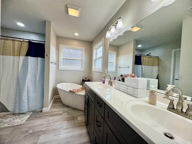 bathroom featuring hardwood / wood-style flooring, vanity, separate shower and tub, and a textured ceiling