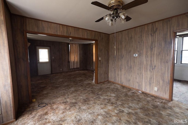 empty room featuring carpet floors, a wealth of natural light, and wood walls