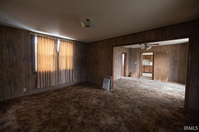 spare room with wooden walls, ceiling fan, and carpet flooring