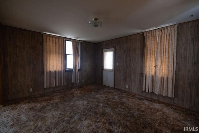 spare room featuring wooden walls and carpet