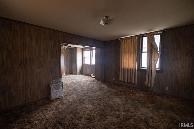 carpeted spare room featuring heating unit and wooden walls