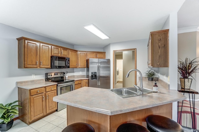 kitchen with sink, appliances with stainless steel finishes, a kitchen breakfast bar, washer / clothes dryer, and kitchen peninsula