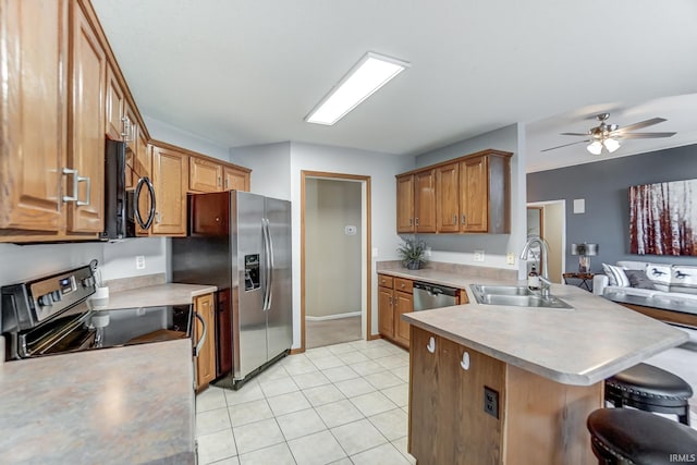 kitchen featuring appliances with stainless steel finishes, sink, a breakfast bar area, light tile patterned floors, and kitchen peninsula