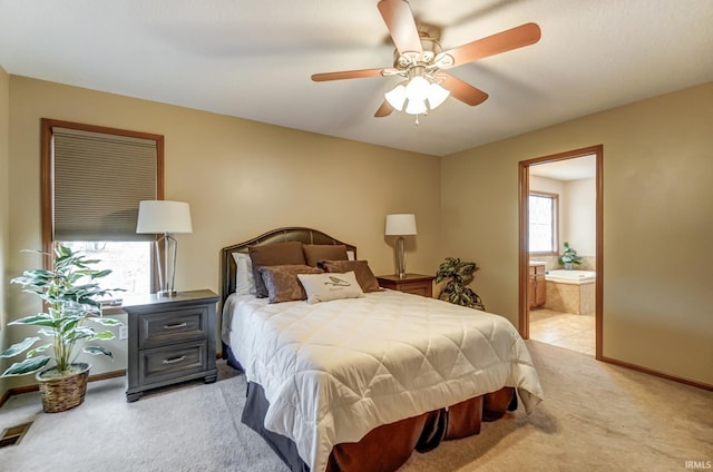 carpeted bedroom with ensuite bath and ceiling fan