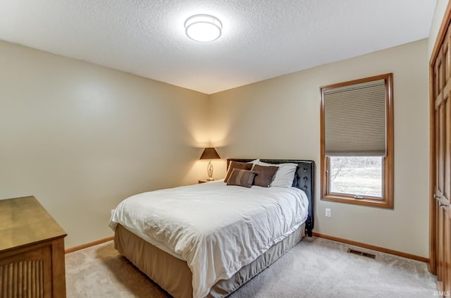 bedroom featuring light colored carpet and a textured ceiling