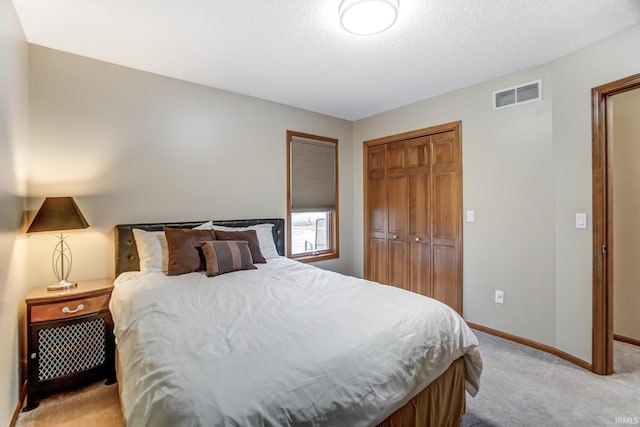 bedroom featuring light colored carpet, a closet, and a textured ceiling