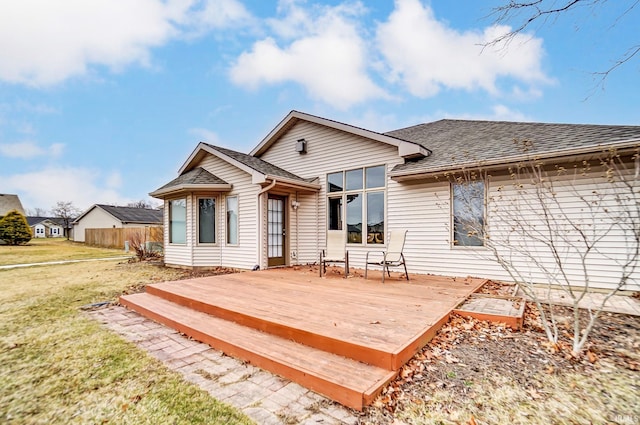 back of property with a wooden deck and a lawn