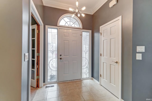 tiled entryway featuring a notable chandelier and crown molding