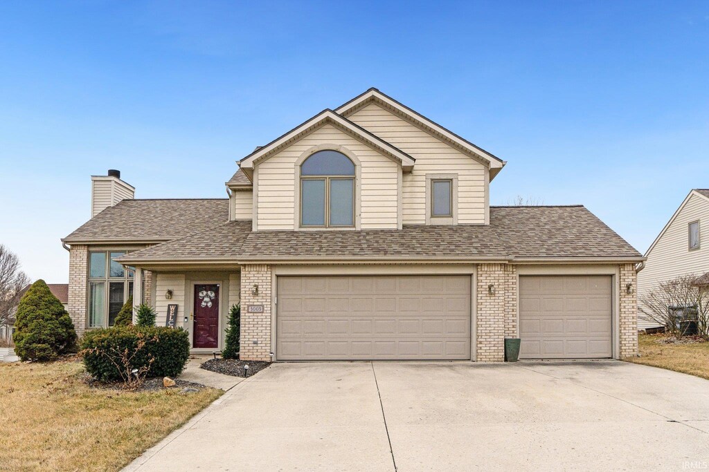 3003 Mariposa Pl, Fort Wayne, IN 46818 - traditional home with brick siding, driveway, a chimney, and roof with shingles