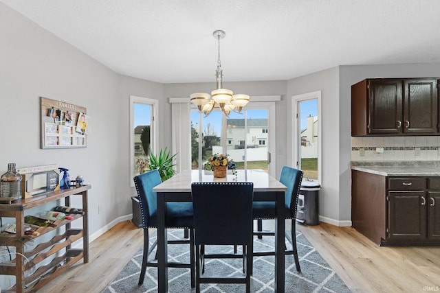 dining room with light wood-type flooring, baseboards, and a chandelier