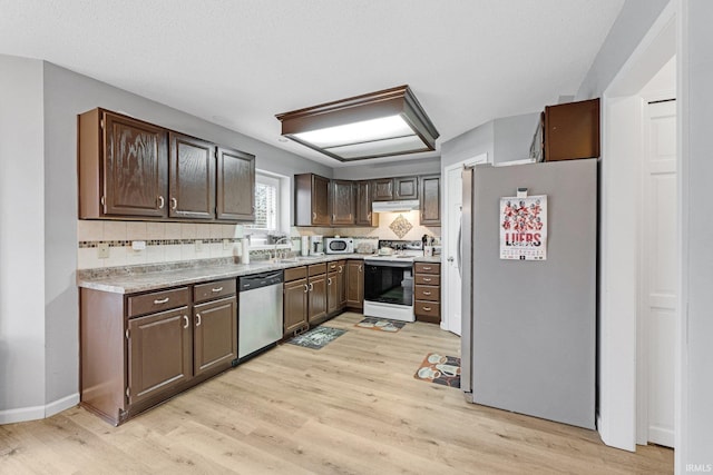 kitchen featuring dark brown cabinetry, appliances with stainless steel finishes, light countertops, under cabinet range hood, and a sink