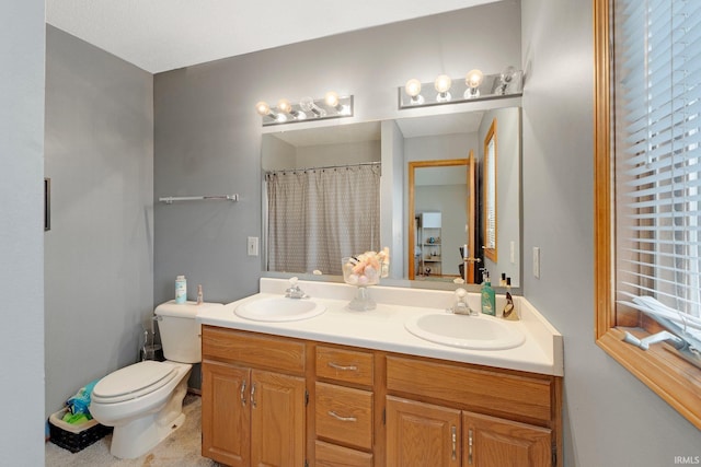 bathroom featuring double vanity, curtained shower, toilet, and a sink