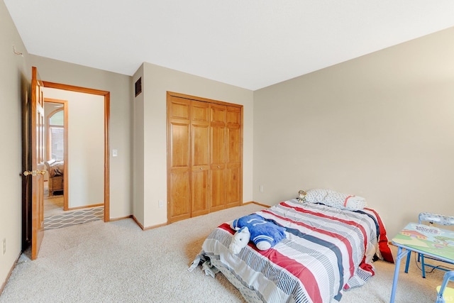 carpeted bedroom with visible vents, baseboards, and a closet