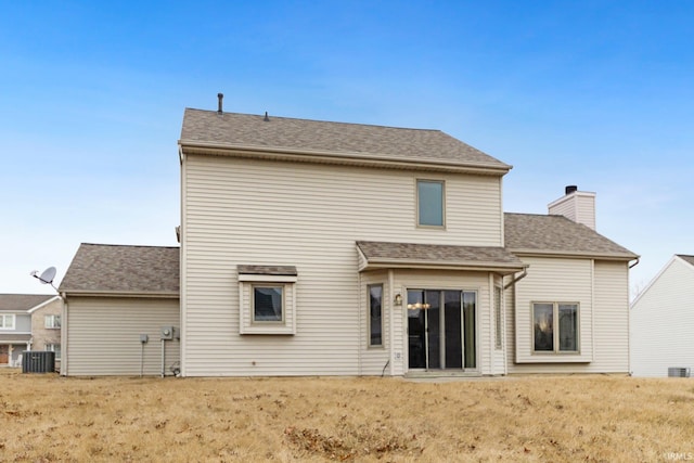 rear view of property with a yard, a shingled roof, a chimney, and cooling unit