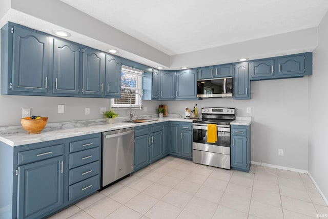 kitchen featuring sink, light tile patterned flooring, stainless steel appliances, and blue cabinetry