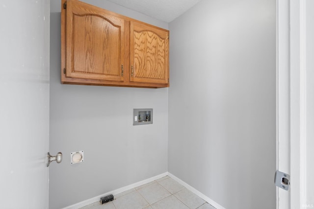 washroom featuring light tile patterned flooring, cabinets, washer hookup, and a textured ceiling