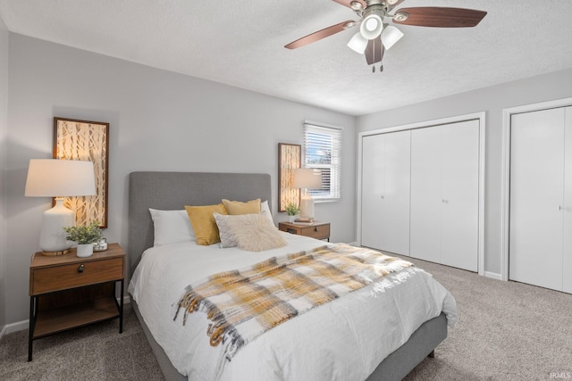 carpeted bedroom with ceiling fan, two closets, and a textured ceiling