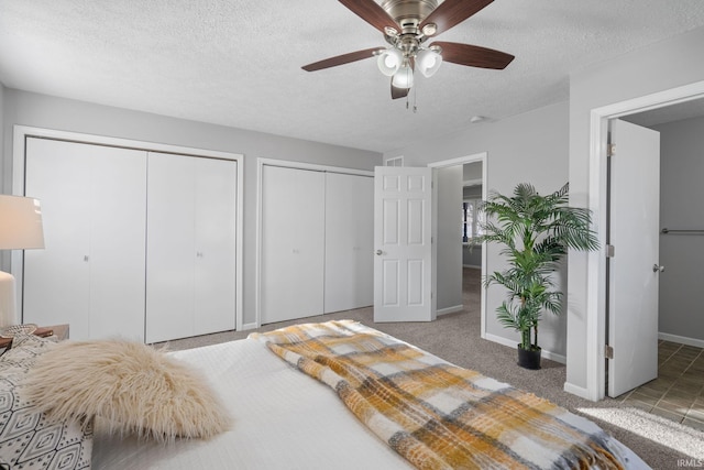 carpeted bedroom with multiple closets, ceiling fan, and a textured ceiling