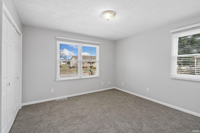 carpeted empty room with a textured ceiling