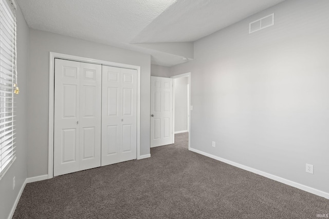 unfurnished bedroom with dark carpet, a closet, and a textured ceiling