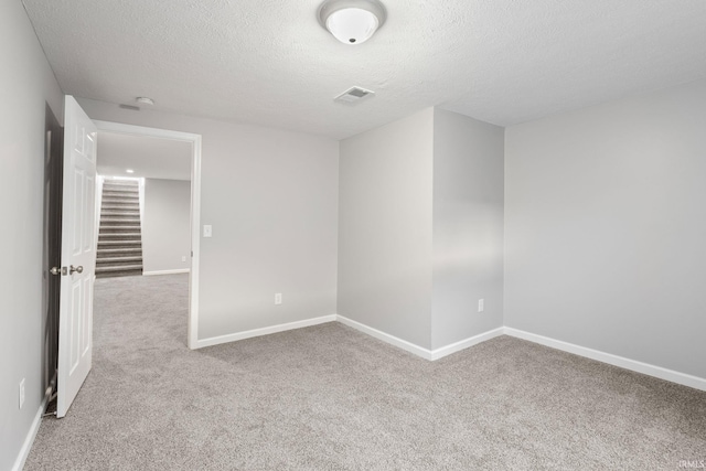 unfurnished room with light colored carpet and a textured ceiling